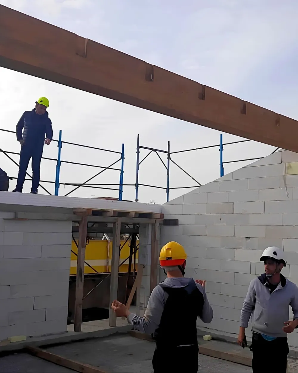 The Edilservizi team on site in safety helmets, under a timber beam and beside the new walls