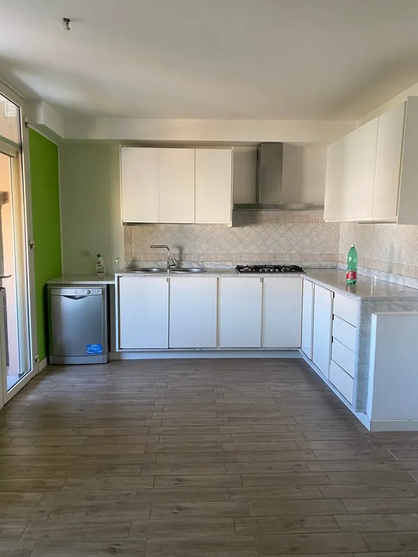 La cucina prima dei lavori, con mobili bianchi e parete verde