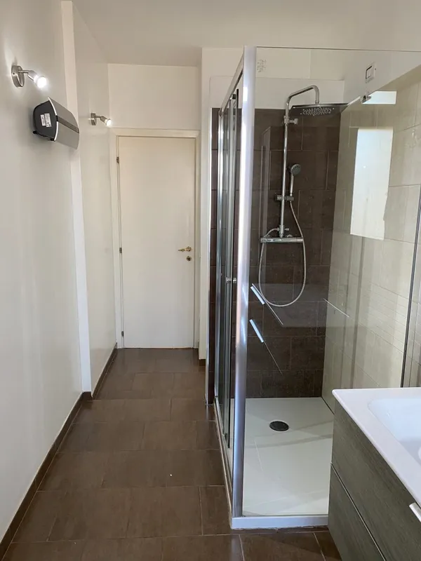Il bagno prima dei lavori, con box doccia e pavimento scuro