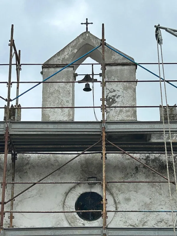 Il campanile a vela con la campana e il rosone durante i lavori, visti dal ponteggio