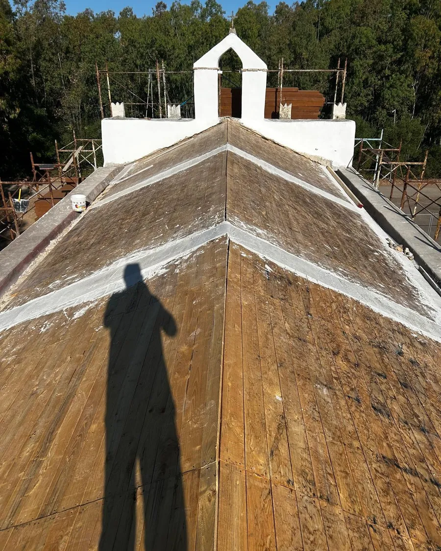 La copertura vista dall'alto con il vecchio tavolato in legno scoperto e il campanile a vela sullo sfondo