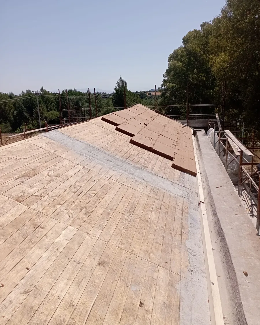 La posa del nuovo tavolato in legno sulla copertura, con il ponteggio lungo il fianco