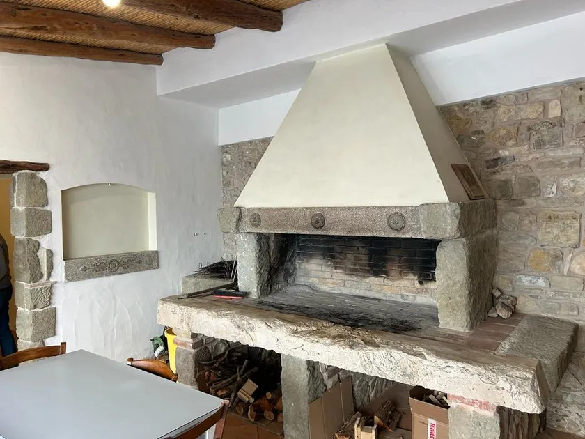 Camino in pietra della villa di Sanluri, con cappa intonacata, architrave in trachite e parete in pietra a vista